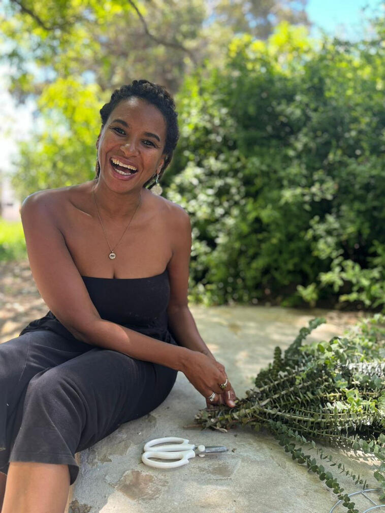 Simone Clarke laughing outdoors in McGregor, making a Christmas wreath with freshly cut greenery.